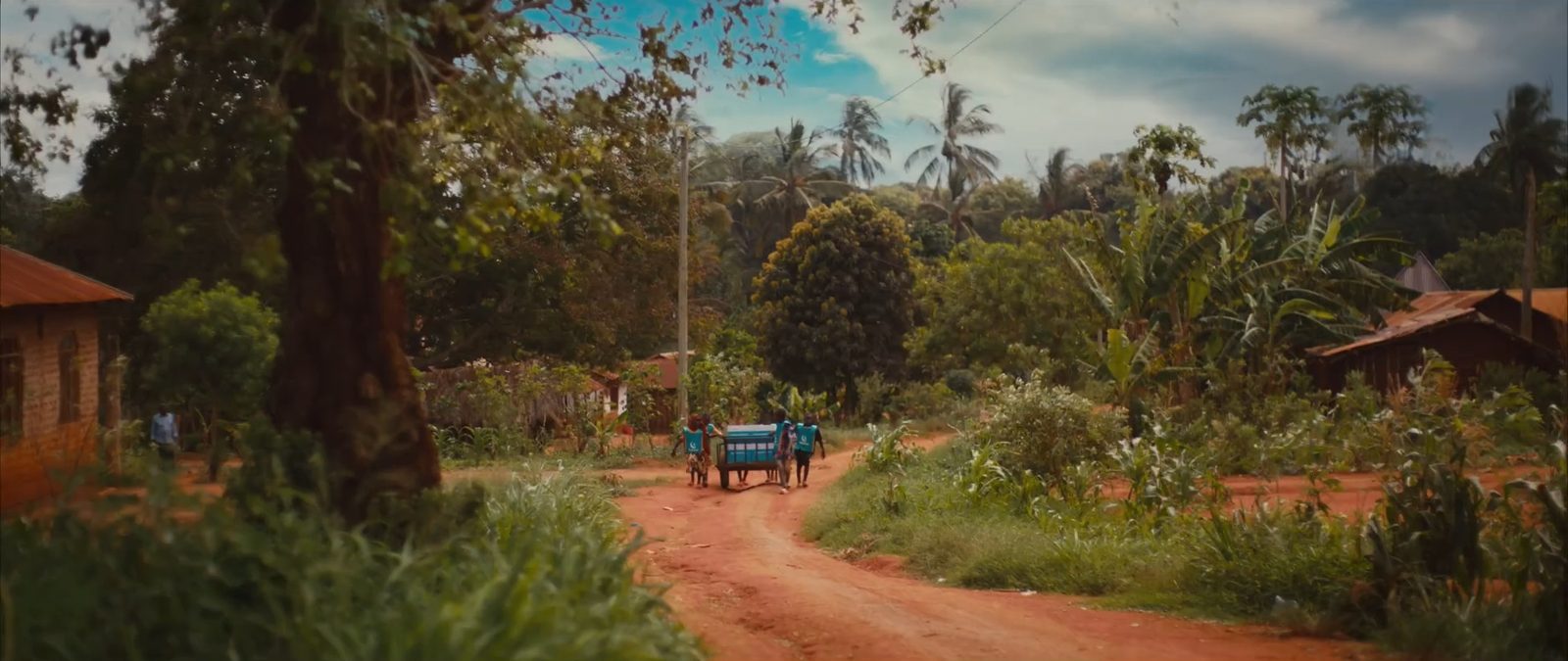 Volunteers push a cart down a red dirt road
