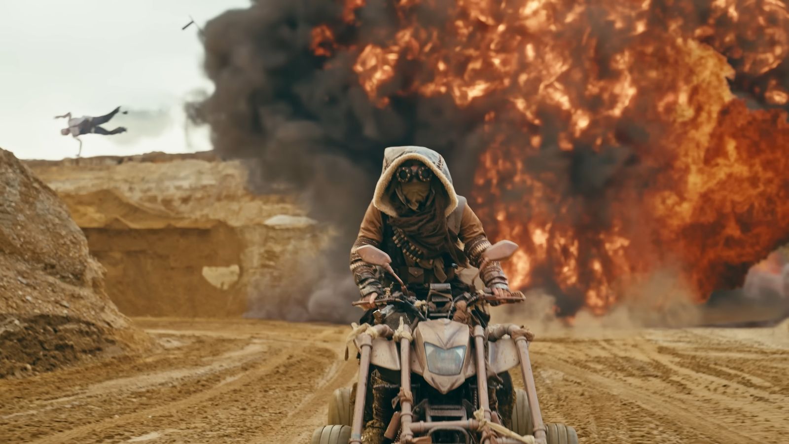 Still: a rider on a desert quad in front of a huge explosion