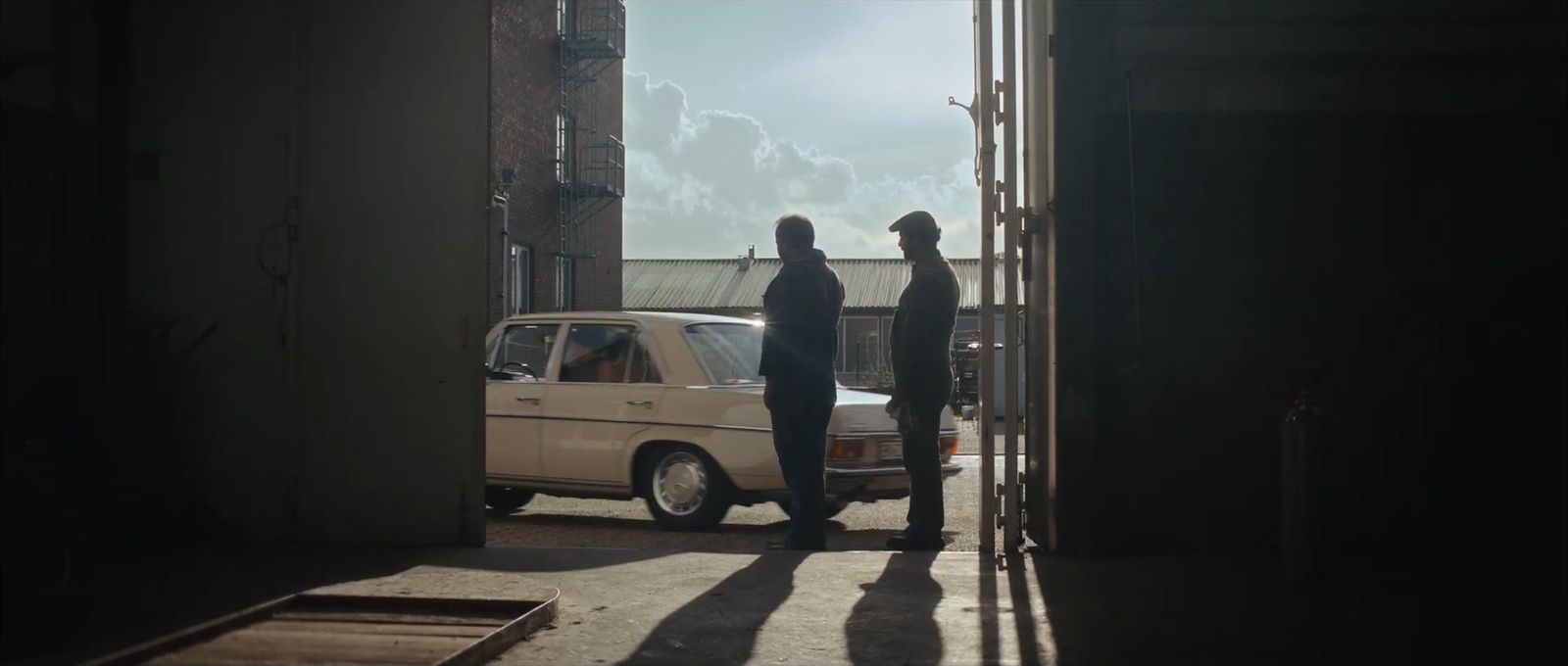 Silhouettes next to a vintage Mercedes in hard backlight