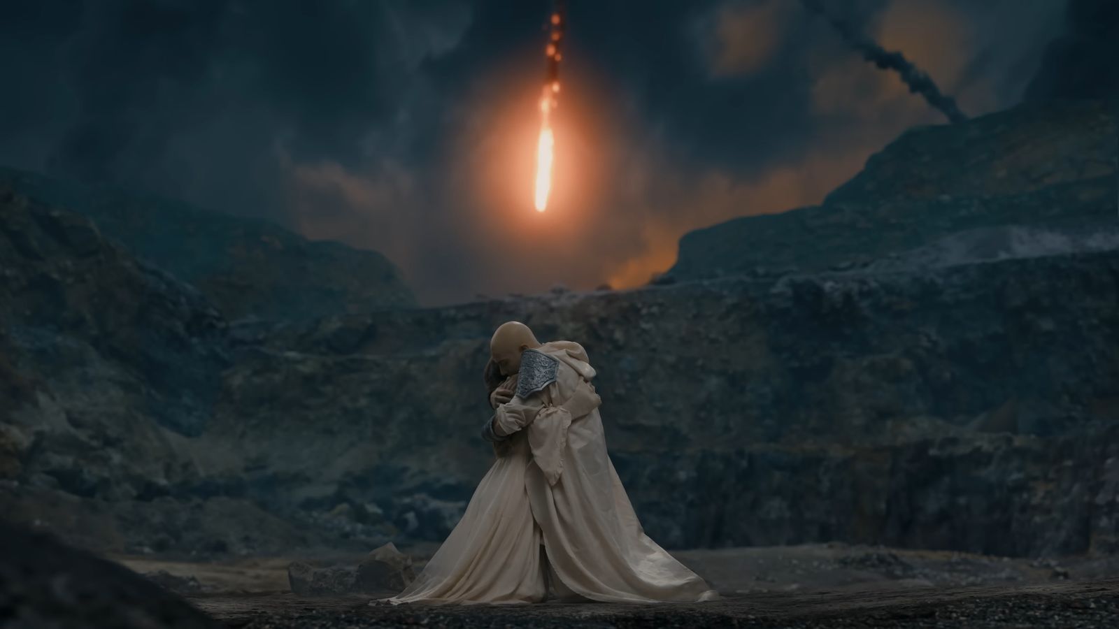 Two figures embrace as a fireball falls from the sky