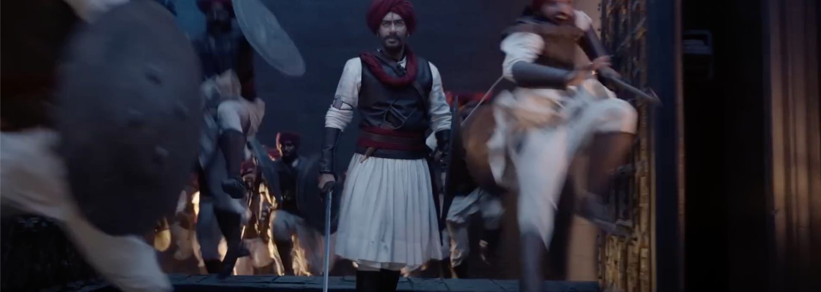 A warrior walks through a battle, sword in hand