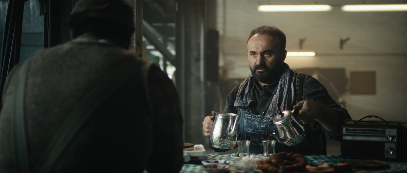 A bearded man pours Turkish tea in a workshop